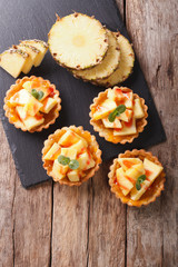 Delicious tartlets with fresh pineapple and jam closeup on the table. vertical top view