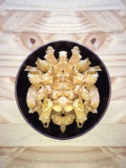 Crispy deep fried wonton in black bowl on wood background
