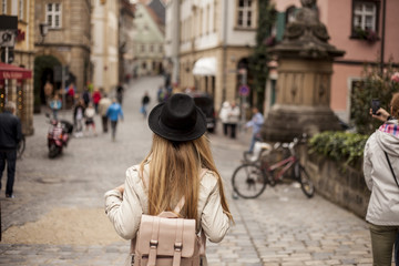 A woman with a hat from the back in ancient Europe city - obrazy, fototapety, plakaty