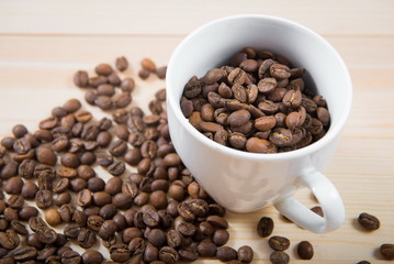 coffee beans in cup. Coffee cup and coffee beans on wooden background. coffee with cinnamon, coffee with additives. Coffee beans and cinnamon sticks
