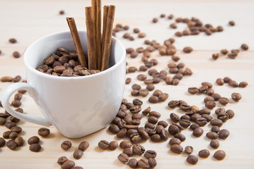 coffee beans in cup. Coffee cup and coffee beans on wooden background. coffee with cinnamon, coffee with additives. Coffee beans and cinnamon sticks
