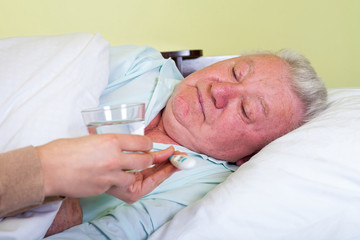 Bedridden elderly man having high temperature