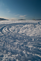 Tyre tracks in the snow going downhill with deep blue sky