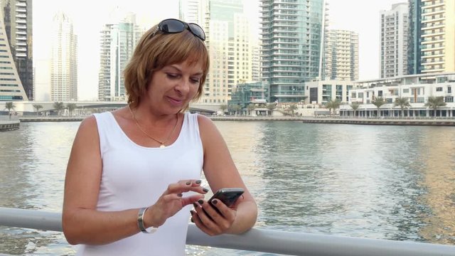 pretty woman with smartphone near the waterfront in Dubai, UAE