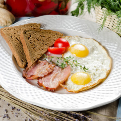 Hearty breakfast. Fried eggs with bacon, rye bread and cherry to