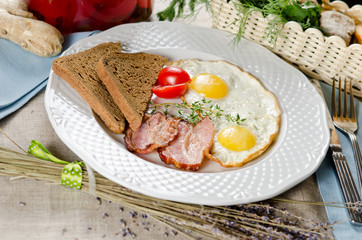 Hearty breakfast. Fried eggs with bacon, rye bread and cherry to