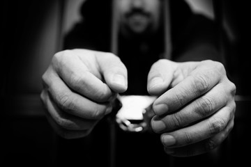 Hands of the prisoner on a steel lattice close up. Prison, man in handcuffs. Abstract. 