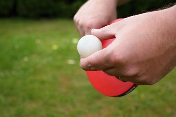 Outdoor table tennis. Man with red table tennis rackets and balls.