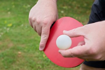 Outdoor table tennis. Man with red table tennis rackets and balls.