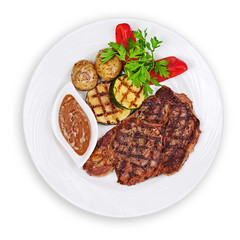Grilled steak, baked potatoes and vegetables on white plate isolated on white background.
