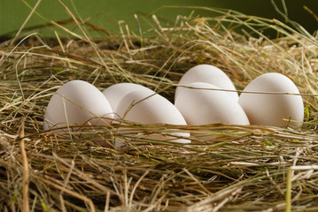 Chicken eggs in the straw. Wooden rustic background.