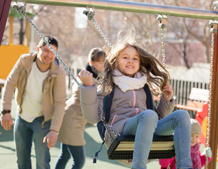 Obraz premium Cheerful family spending time at children swings