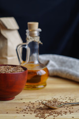 Flax seeds on spoon and linseed oil in glass jug on wooden cutti