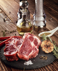 Raw pork neck steak on a stone plate.