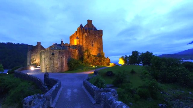 Path to illuminated Eilean Donan Castle over the lake in Scotland, UK
