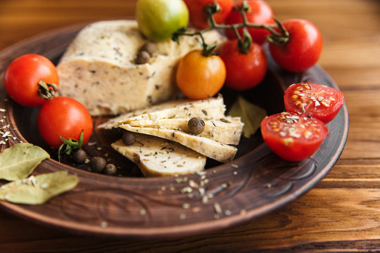 homemade cheese,tomatos with herb spice in pottery.wooden background.
