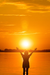 Woman is holding sun  in water at sunset