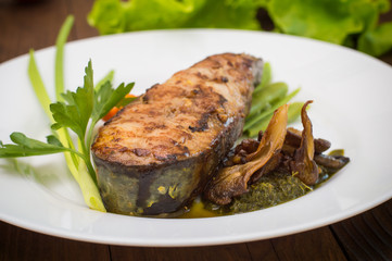 Tasty baked fish on plate on table close-up. Wooden background. Top view. Close-up