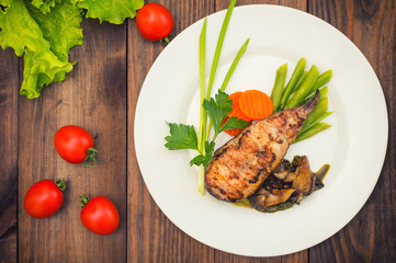 Tasty baked fish on plate on table close-up. Wooden background. Top view. Close-up