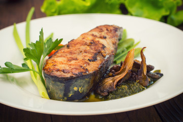 Tasty baked fish on plate on table close-up. Wooden background. Top view. Close-up