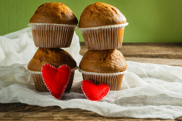 Cupcakes on roustic wooden background. Hearts made of felt.
