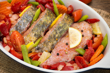 Sea bass with vegetables. marinated fish with vegetables for cooking in the oven. Wooden background. Top view. Close-up