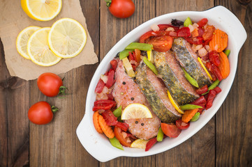 Sea bass with vegetables. marinated fish with vegetables for cooking in the oven. Wooden background. Top view. Close-up