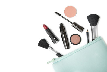 Make up products spilling out of a pastel blue cosmetics bag, isolated on a white background and blank space at side