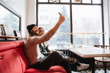 Obraz premium Side view of Young Couple making selfie in cafe