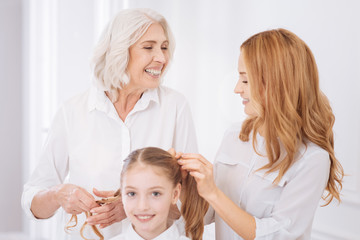 Cheerul family members putting hair of girl in a plait