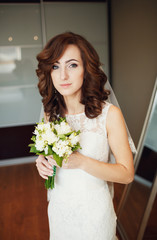 The bride with bouquet  stands  in the room