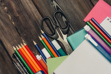 Scissors, markers and pencils lie under sheets of paper