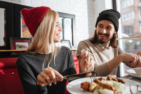 Side view of smiling couple eating in cafe