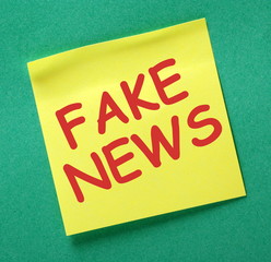 The words Fake News in red text on a yellow sticky note as a reminder to be aware of hoaxes and disinformation for propaganda uses