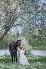 Fototapeta na wymiar Girl on black horse in blossom garden