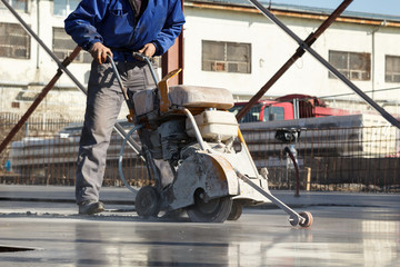 Worker with concrete cutting machine in motion