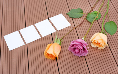 Empty notepaper with pink rose flower on wooden.