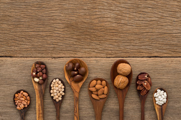 Different kind of beans and lentils in wooden spoon on wood back