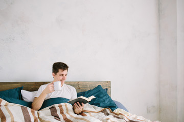 Fototapeta premium Man reading a book on his bed at home