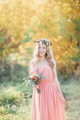 Obraz na płótnie Canvas Beautiful bridesmaid in a pink dress with a wreath on his head.
