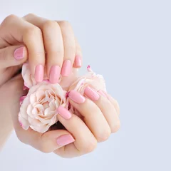 Foto auf Acrylglas Hands of a woman with pink manicure on nails and roses © nmelnychuk