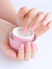 Hands of a woman with pink manicure with cream