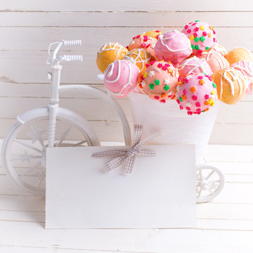 Empty tag and bright cake pops  in decorative bicycle on white w