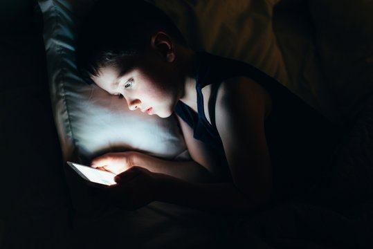 7 years old child boy using smartphone at night