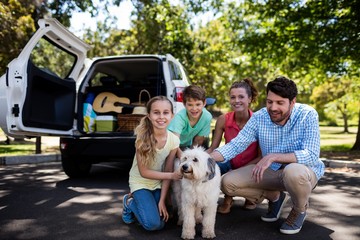 Happy family sitting in the park with their dog