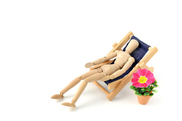 Fototapeta na wymiar wooden mannequin taking sunbath in deck chair