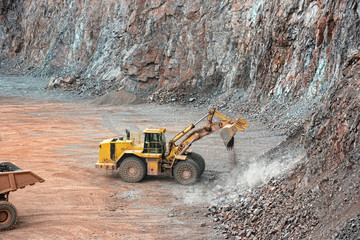 earthmover in a open pit mine quarry. porphyry rock - obrazy, fototapety, plakaty