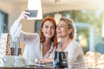 mother and her daughter in a cafe taking a selfie with a phone