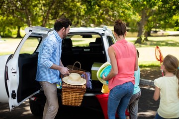 Family placing picnic items in car trunk