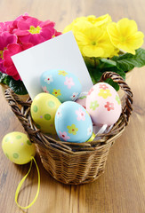 Fototapeta na wymiar Easter eggs in a basket with notice paper copy space